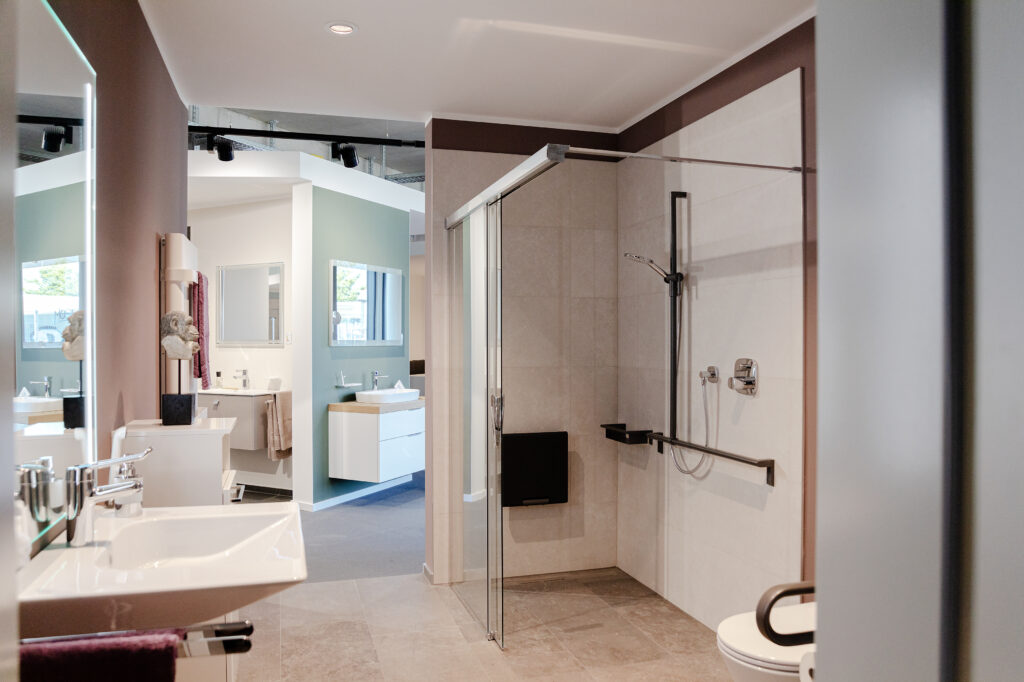 Helles, barrierefreies Badezimmer mit bodengleicher Dusche, Haltegriffen, Klappsitz und modernen Waschtischlösungen.